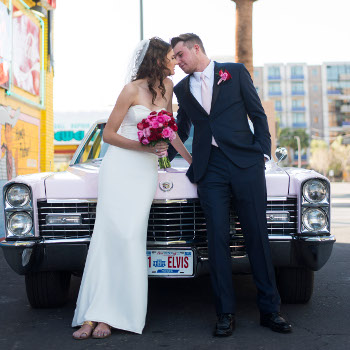 Traditional Las Vegas Wedding Couple in Front of Pink Cadillac Leaning in for a Kiss